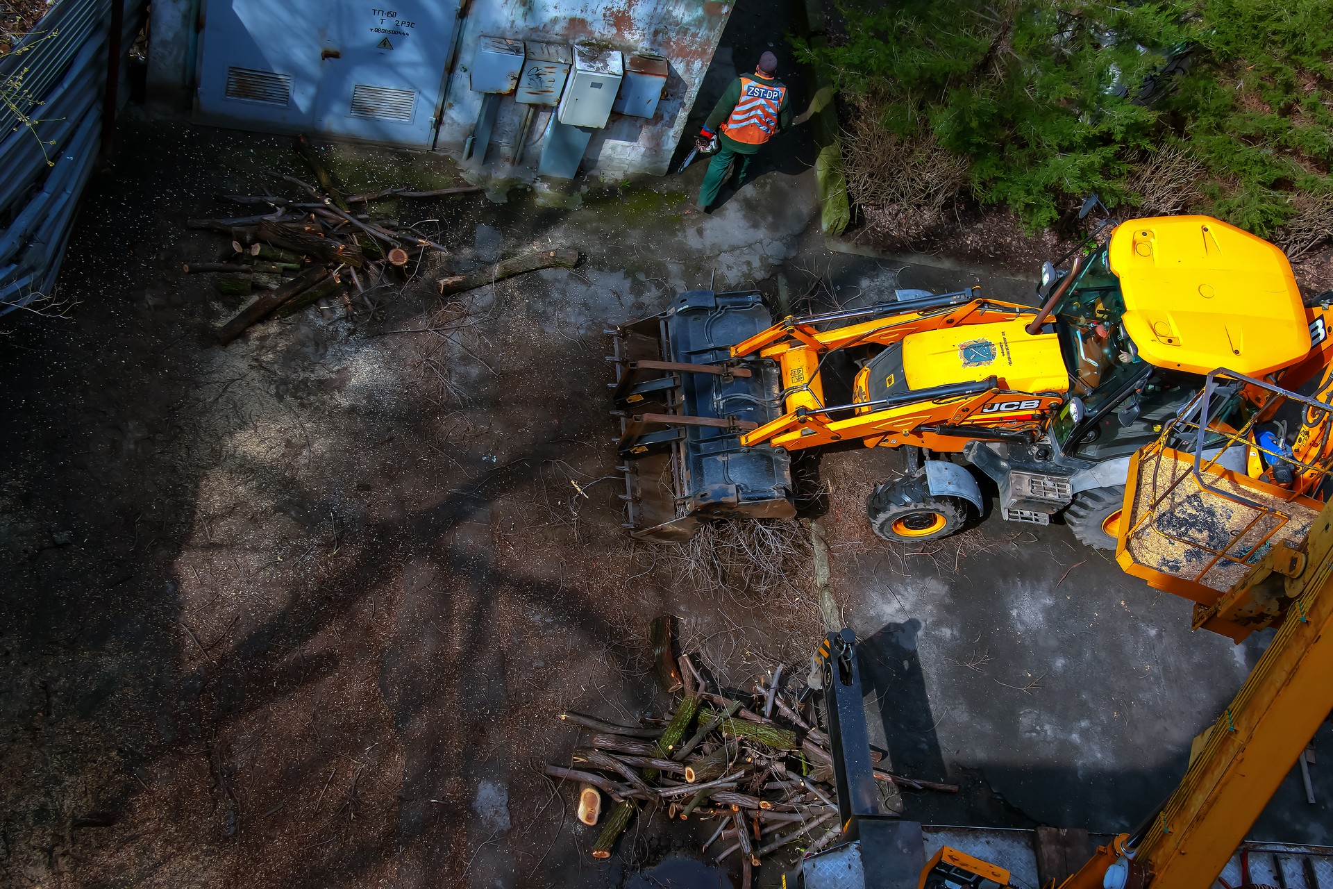 A bulldozer collects branches after pruning trees. View from above